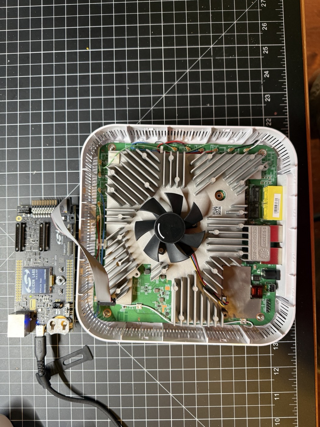 W1700K router mainboard connected to a Silicon Labs debugger through its J10 header